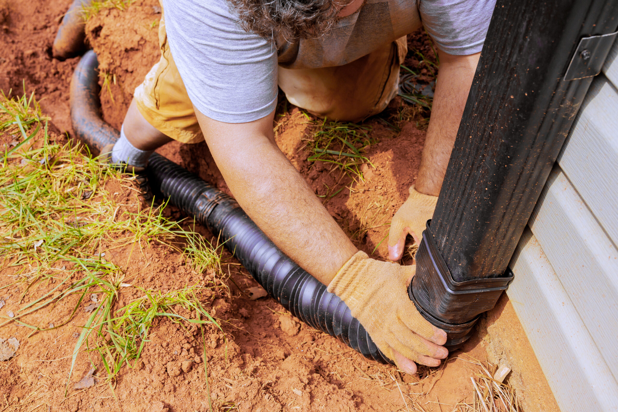 Man installing flexible gutter extension drainage pipe connector downspout